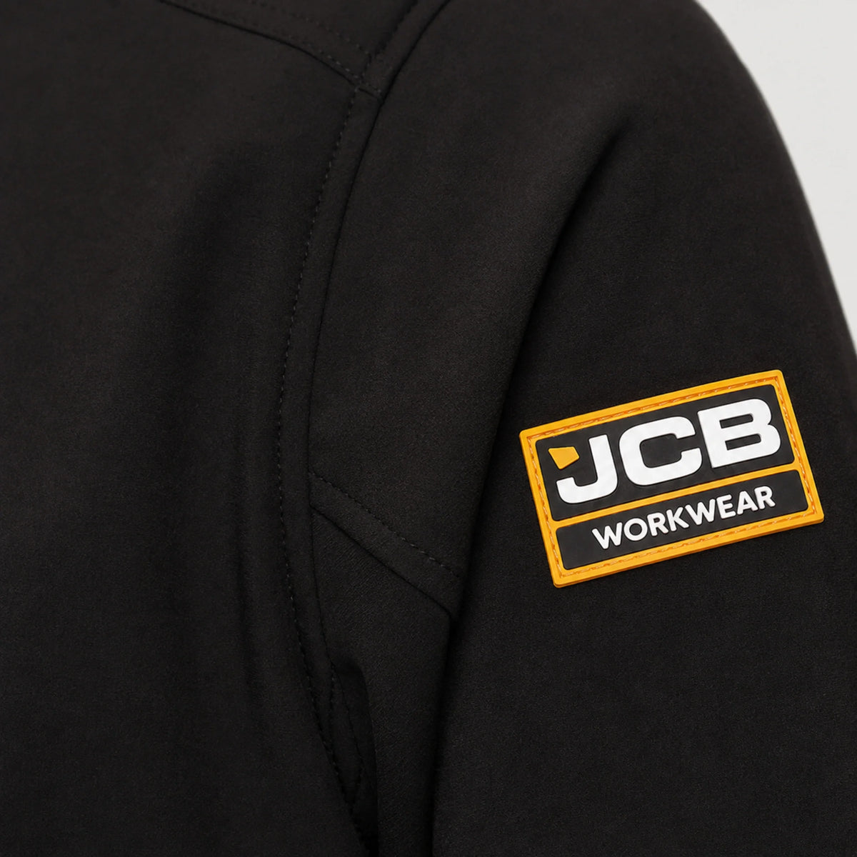 Zbliżenie na naszywkę JCB Workwear na rękawie czarnej kurtki roboczej softshell