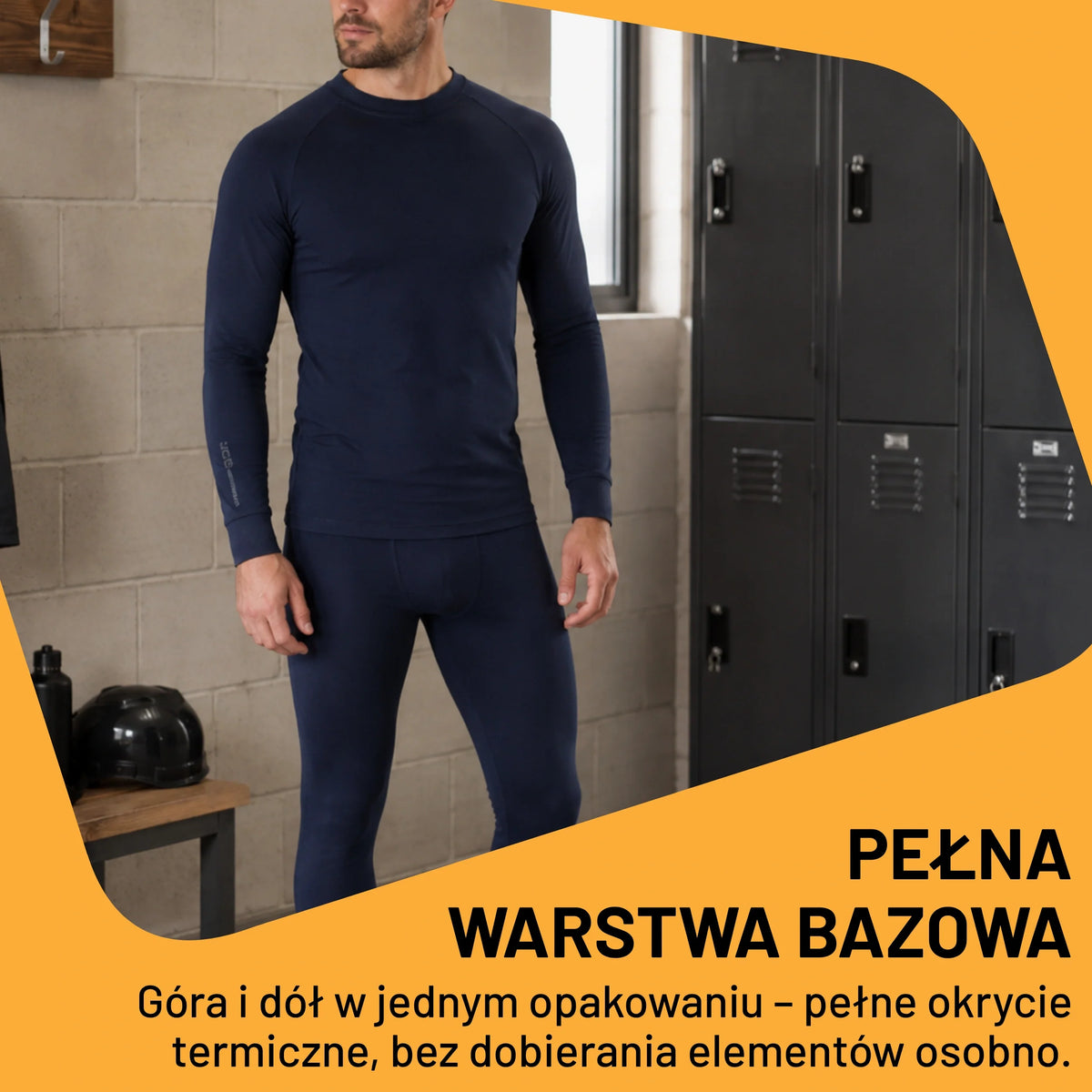 Mężczyzna w granatowym komplecie bielizny termoaktywnej JCB przy szafkach, tekst Pełna warstwa bazowa