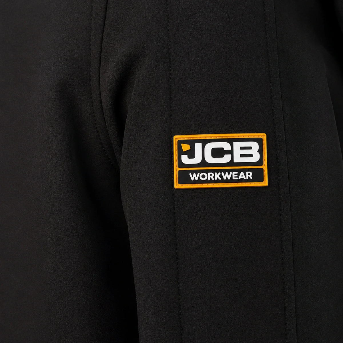 Zbliżenie na naszywkę JCB Workwear na rękawie czarnej kurtki softshell